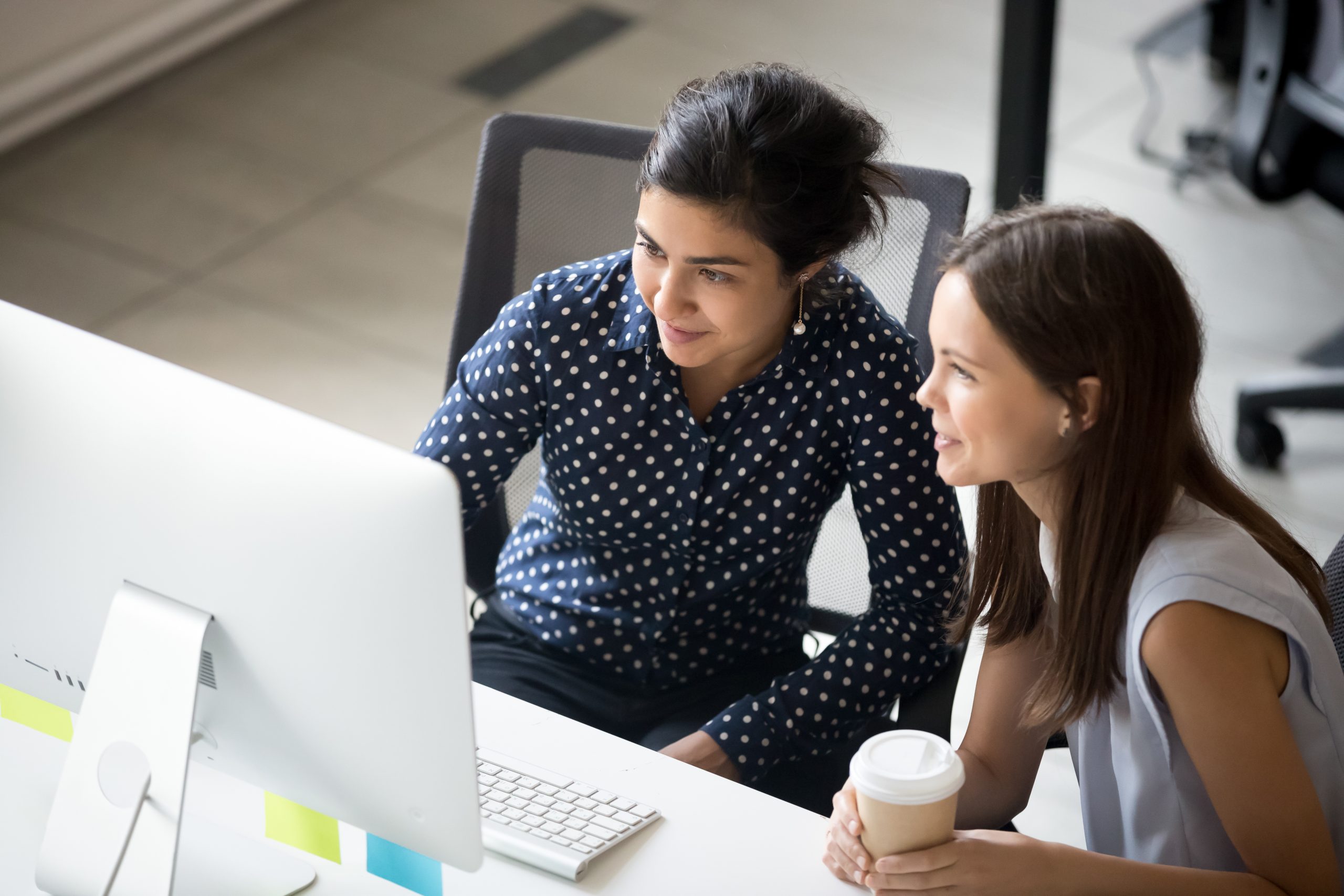 two women having a conversation in front of a computer
