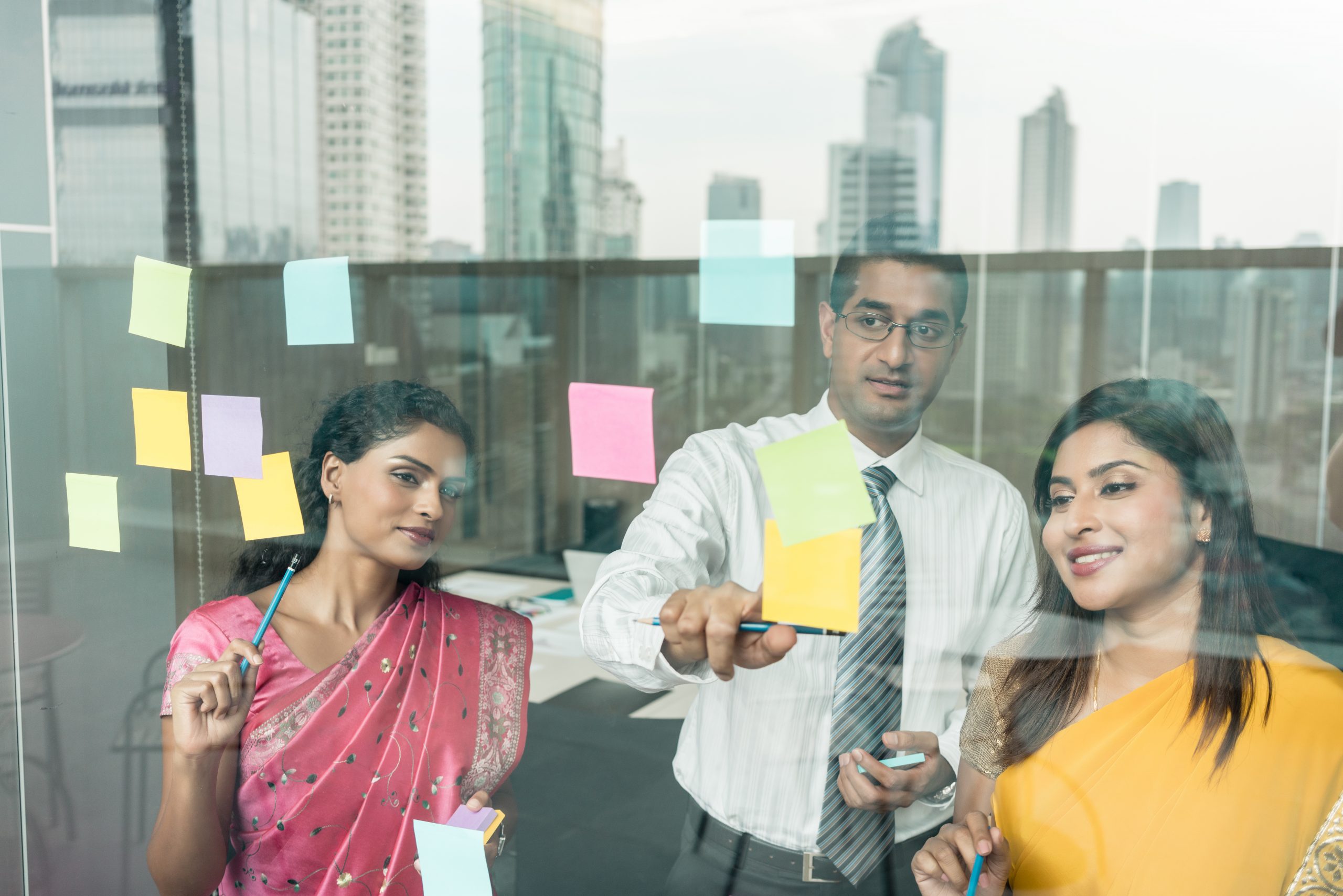 two female indian women and indian man sharing ideas on post its