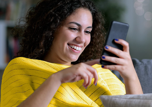 Woman smiling while staring at her cellphone